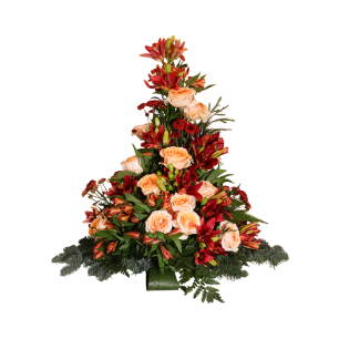 Blomsterarrangemang i form av en pyramid med röda liljor och persikofärgade rosor, omgivna av gröna blad och granris.